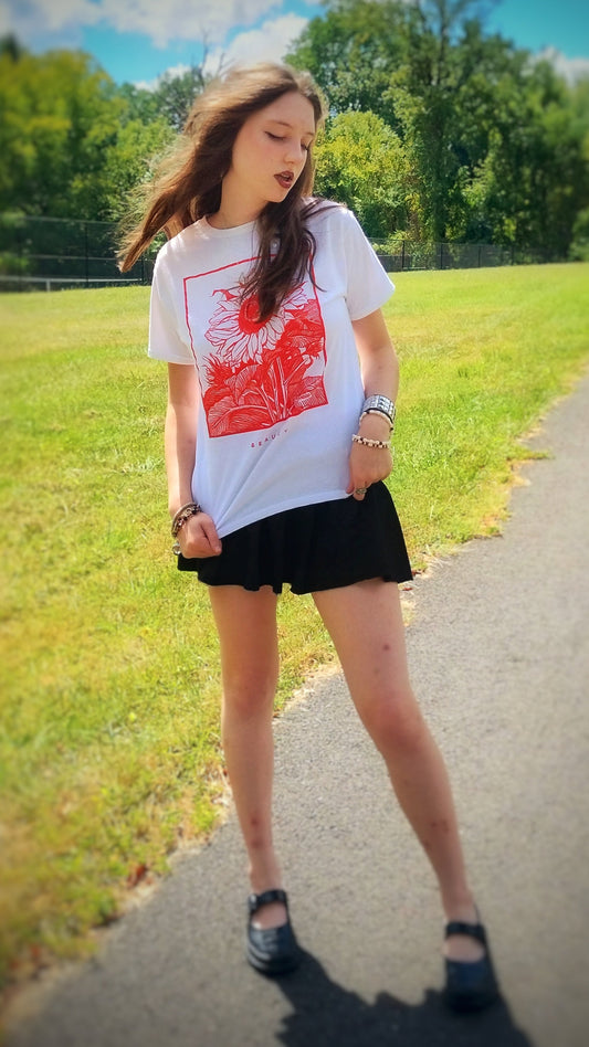 Woman wearing a white t-shirt with a red graphic and black skirt outdoors.